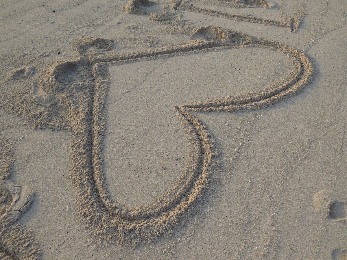 Heart drawn in sand on a beach.