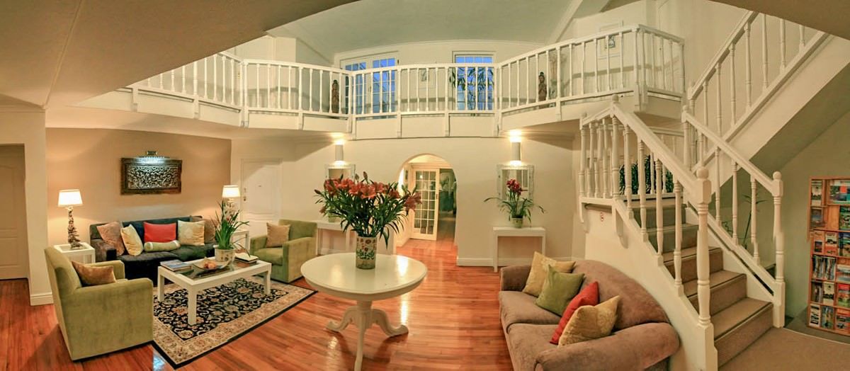 Spacious living room with a mezzanine level, light wood floors, and white railings.