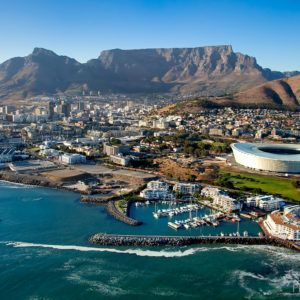 Cape Town, South Africa cityscape with Table Mountain, waterfront, marina, stadium, and blue sky.