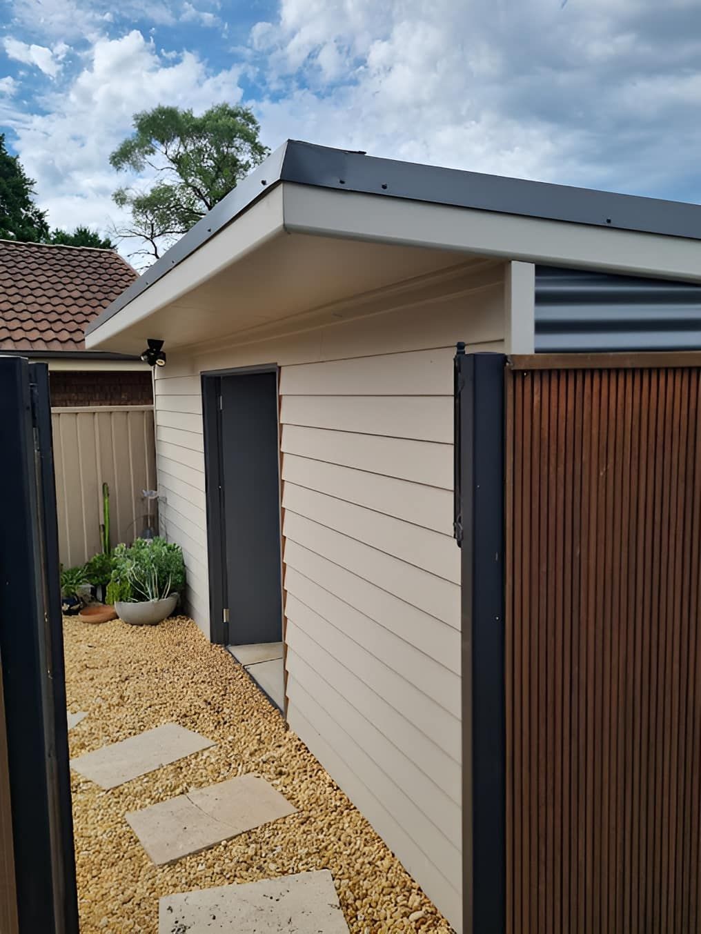 A White Building With A Black Door And A Wooden Fence — Canyon Carpentry in Redridge, QLD