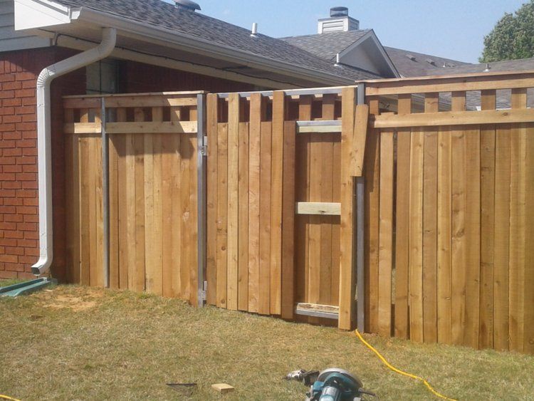 A wooden fence is being built in front of a brick house
