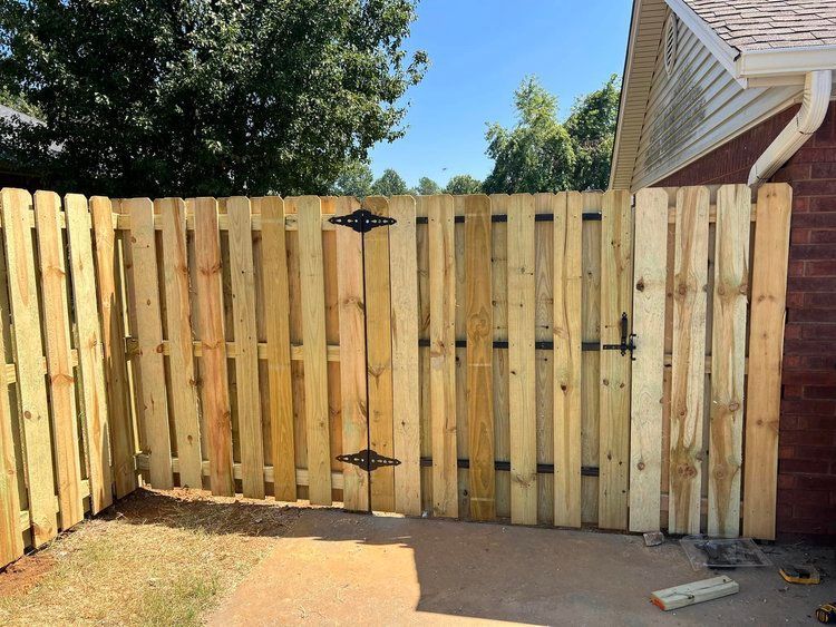 A wooden fence with a gate is being built in front of a brick house.