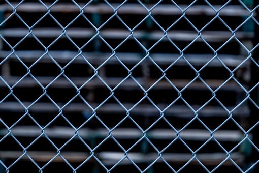 A close up of a chain link fence with a black background.