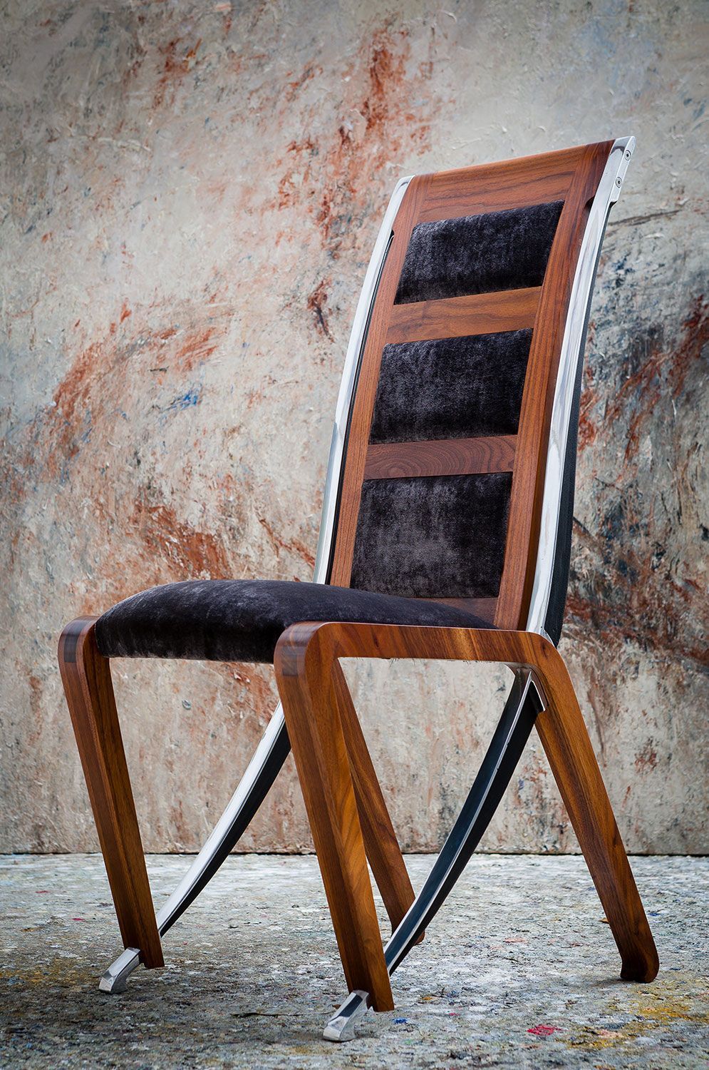 A  bespoke wooden chair with a black cushion is sitting in front of a wall.