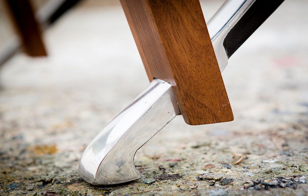 A close up of a wooden table with a metal leg handcrafted by a furniture maker