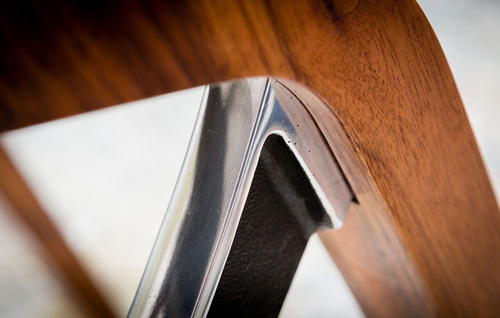 A close up of a custom build wooden dining chair with a metal leg