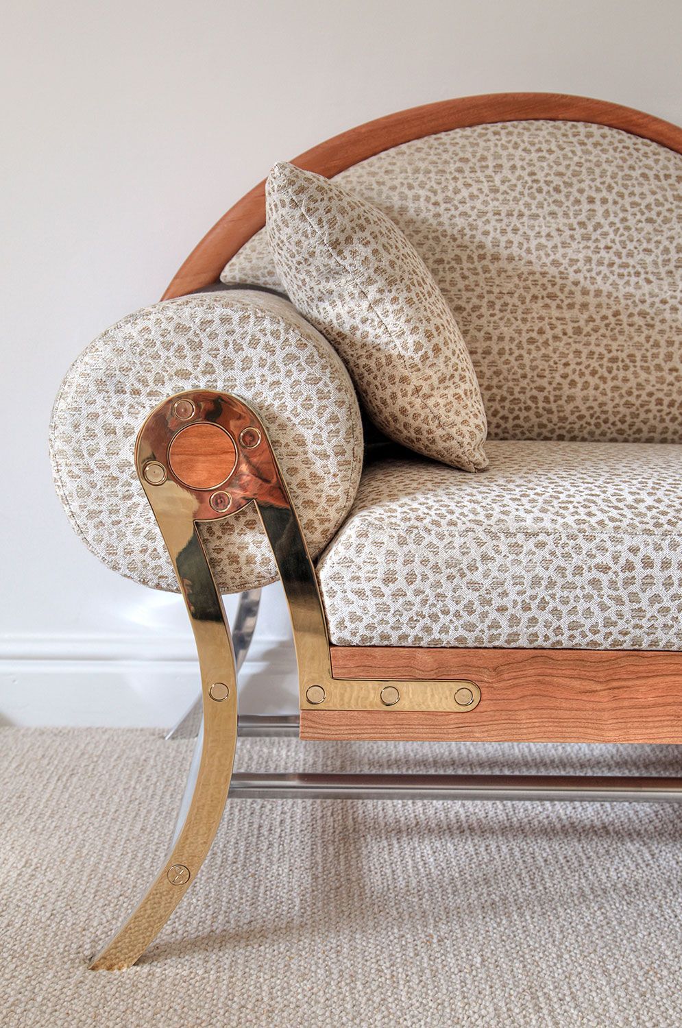 A close up of a designer couch with a leopard print fabric and a brass arm.
