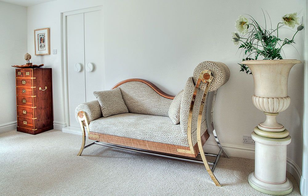 A tailor made daybed is sitting in a room next to a vase of flowers.