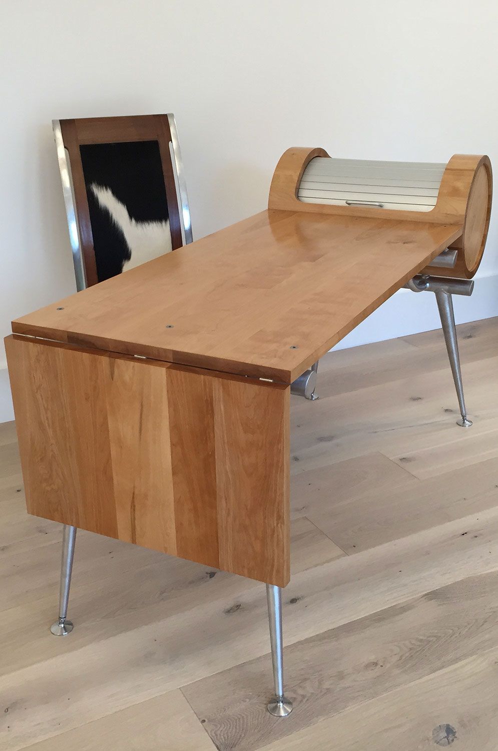 A Unique Handcrafted wooden table is sitting on a wooden floor next to a chair.