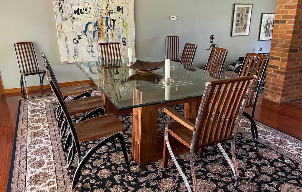 A dining room with a luxury glass table and tailor made wooden dining chairs.