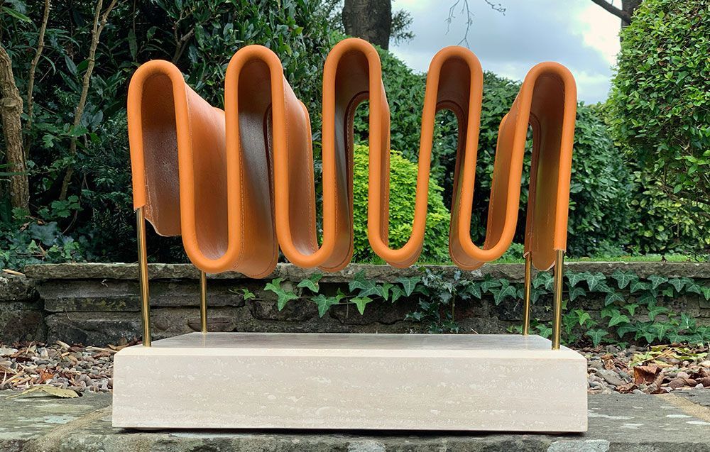 A creative leather magazine rack is sitting on top of a concrete base in a garden.