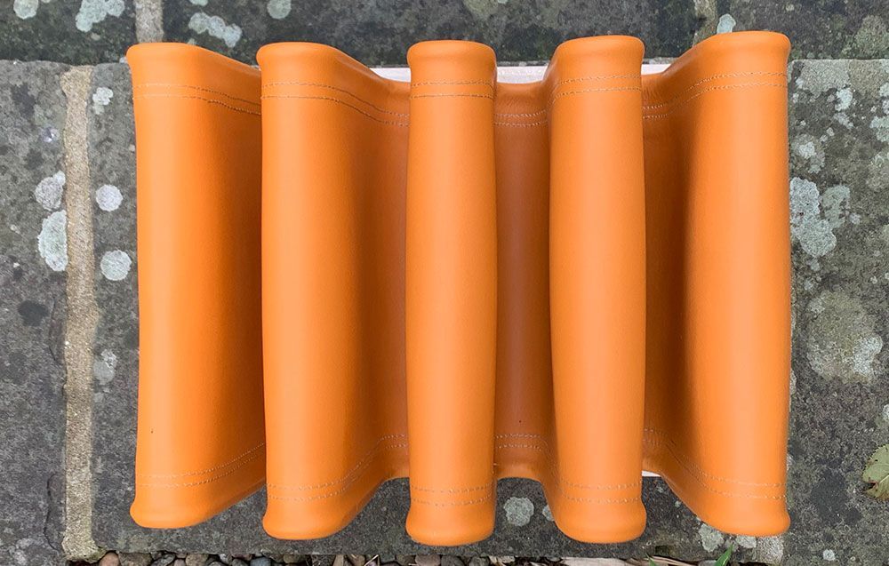 A row of orange leather sitting on top of a concrete surface.