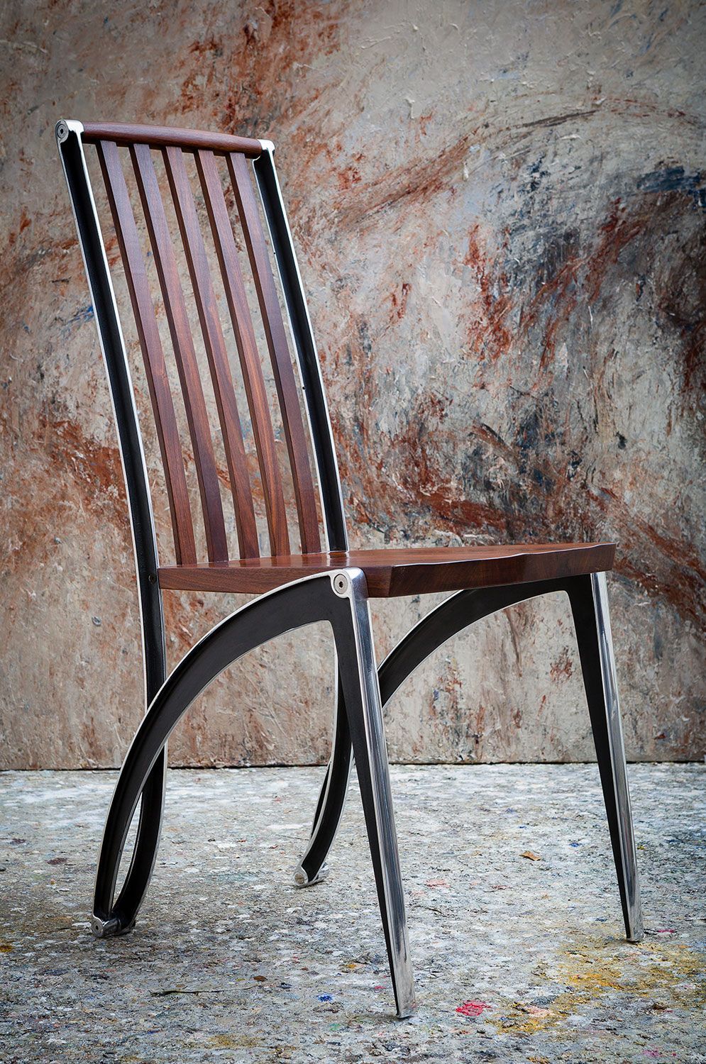 A modern designer wooden chair with metal legs is sitting in front of a wall.