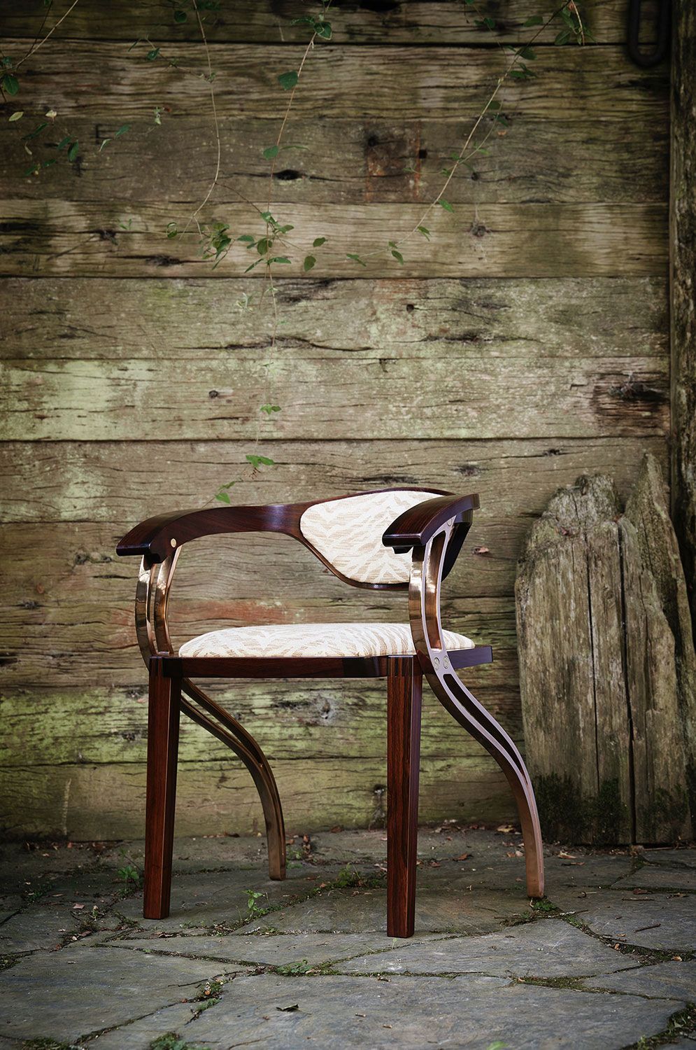 A designer wooden dining chair with a unique design is sitting in front of a wooden wall.