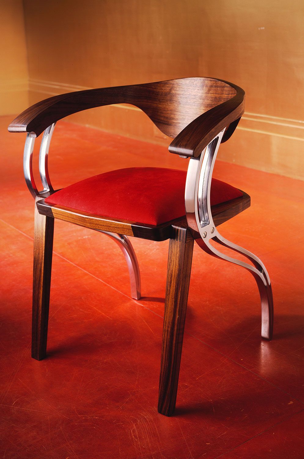 A  unique designer wooden chair with a red cushion sits on a red floor