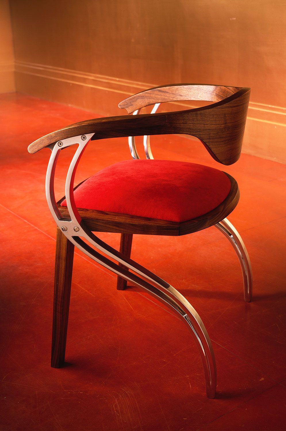 A  custom designed and crafted dining chair with a red cushion is sitting on a red carpet