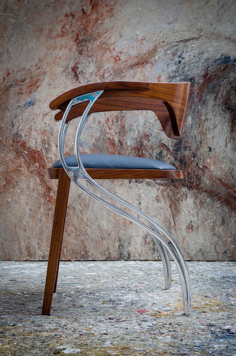 Hand crafted and designer chair with a rope attached to it is sitting in front of a wall.