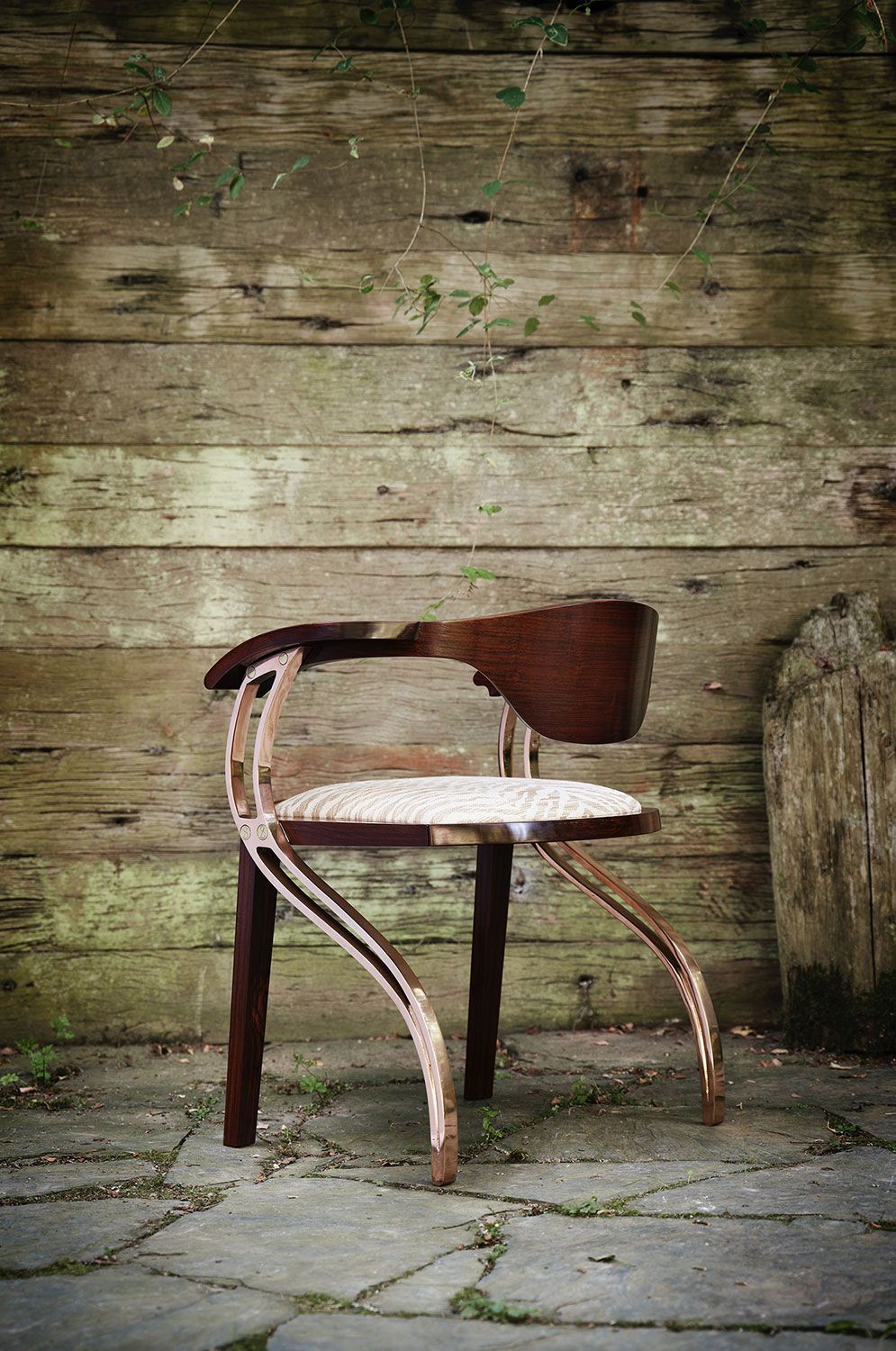 A wooden dining chair is sitting in front of a wooden wall.