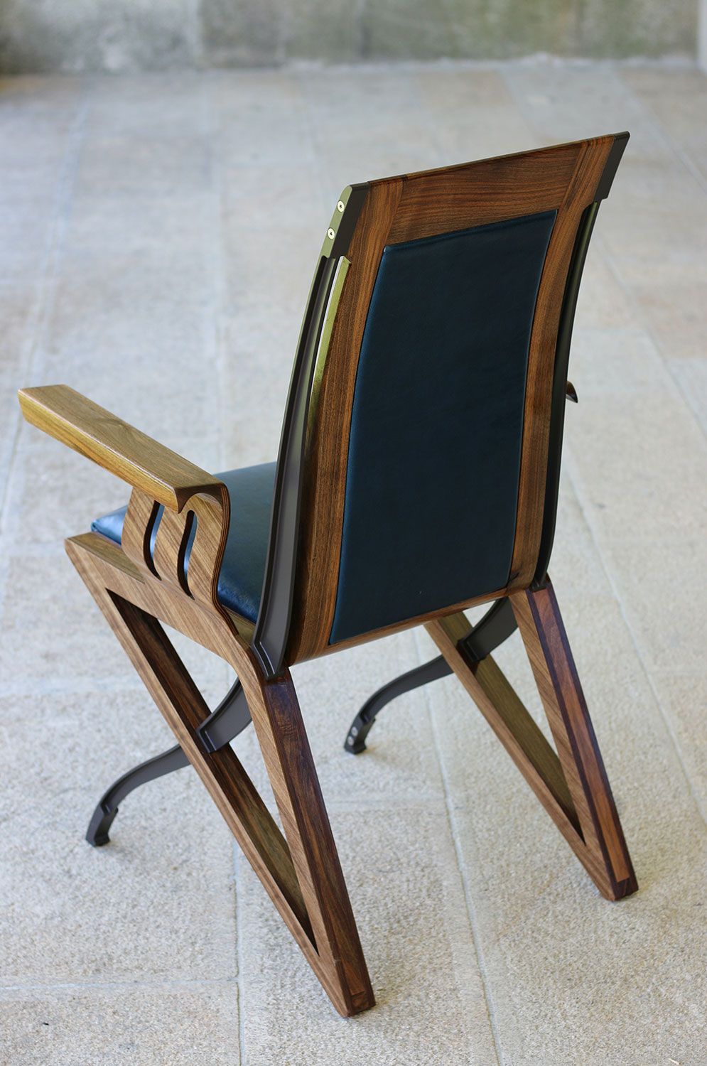 The back of a bespoke wooden chair with a blue cushion