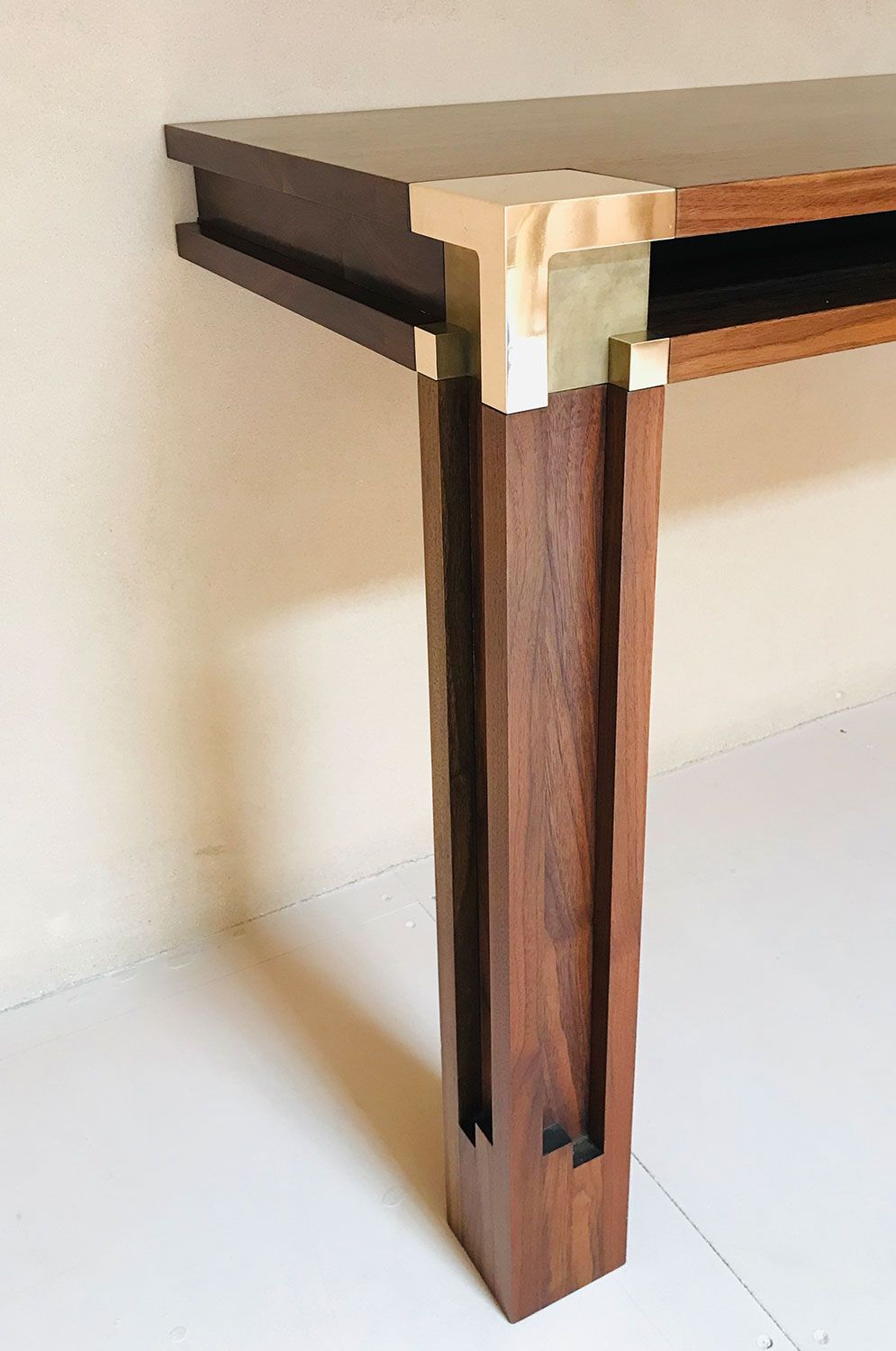 A wooden table with a brass corner is sitting on a white floor.