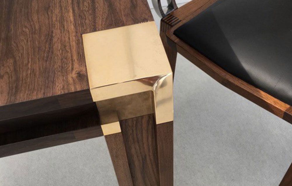 Scanalatto table top quality woodwork with a brass leg next to a chair.