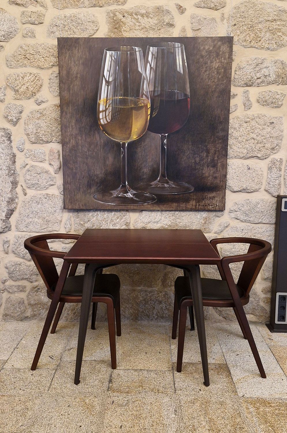 Bespoke table and chairs in front of a painting of wine glasses on a wall inside a café shop