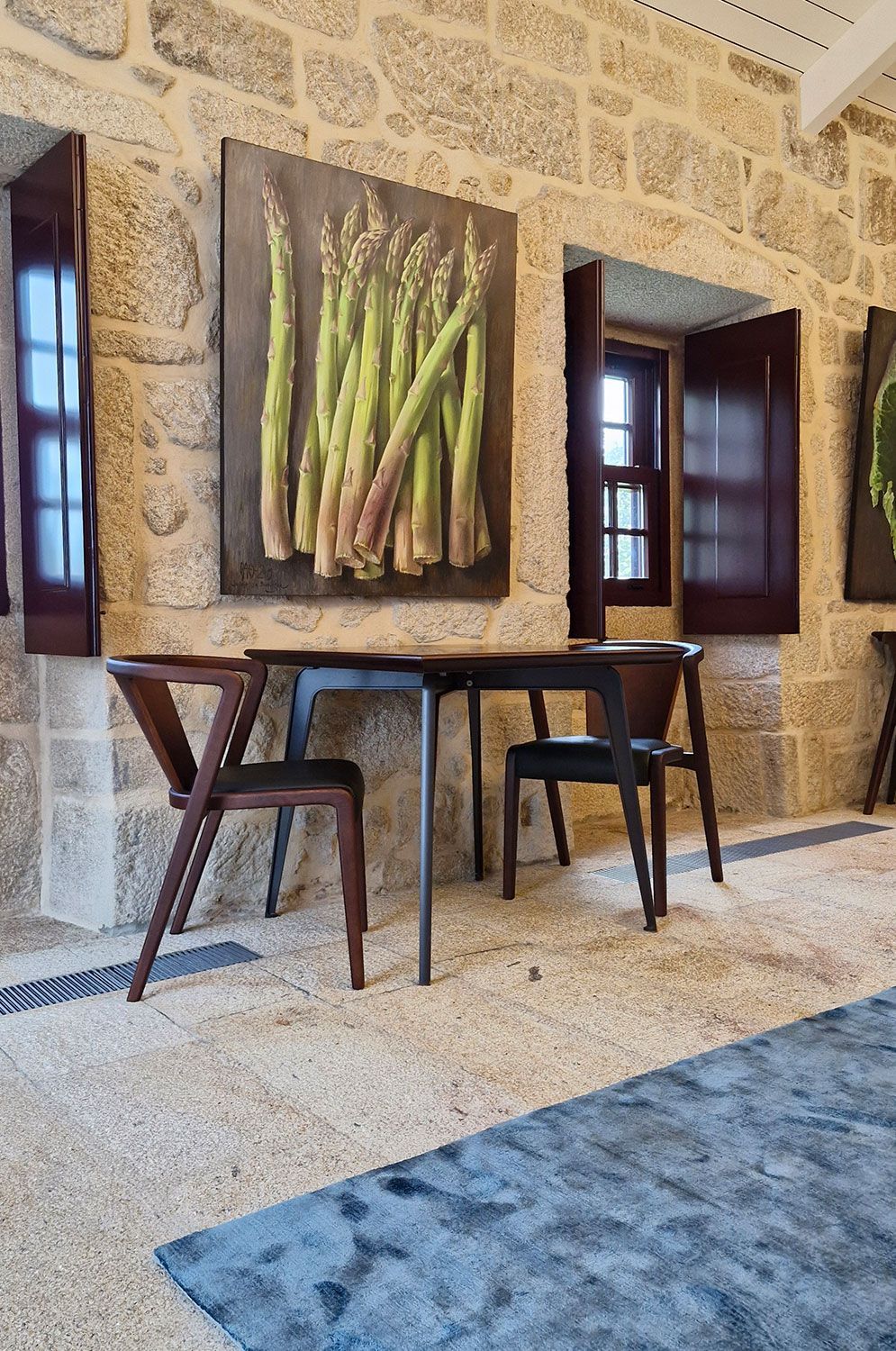 A room with a table and chairs and a painting of asparagus on the wall.
