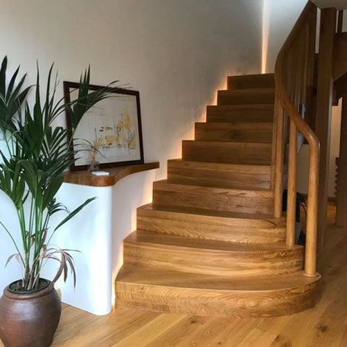A  custom designed wooden staircase with a potted plant next to it.