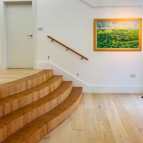 A handcrafted wooden staircase with a picture on the wall above it.