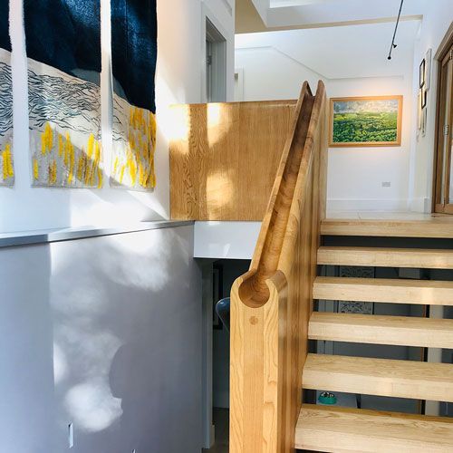 A handcrafted wooden staircase fitted in a room with a picture on the wall above it