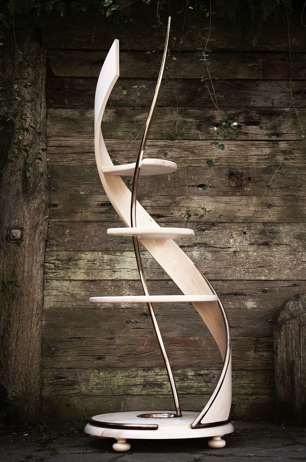A wooden  handcrafted shelf is sitting in front of a wooden wall.