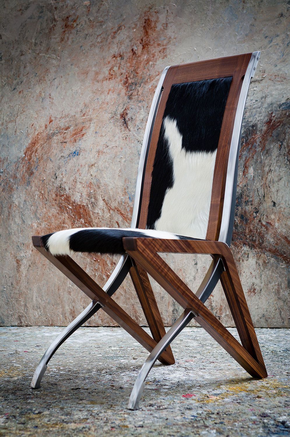 A unqiue wooden chair with a black and white cowhide seat