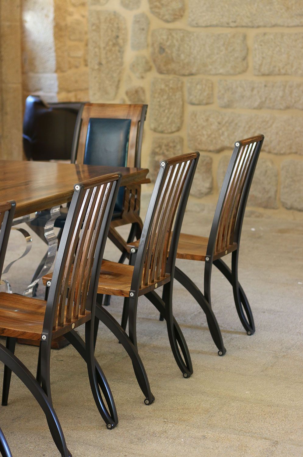 Handcrafted designer table and chairs in a room with a stone wall
