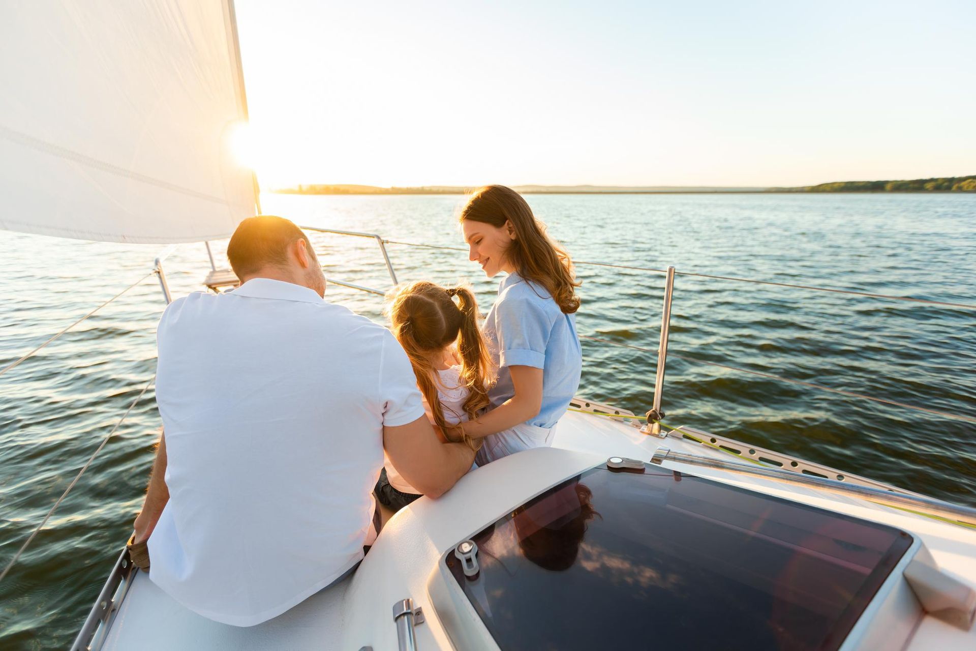 A family is sitting on a sailboat in the water.