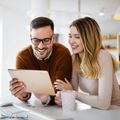 A man and a woman are looking at a computer screen and smiling