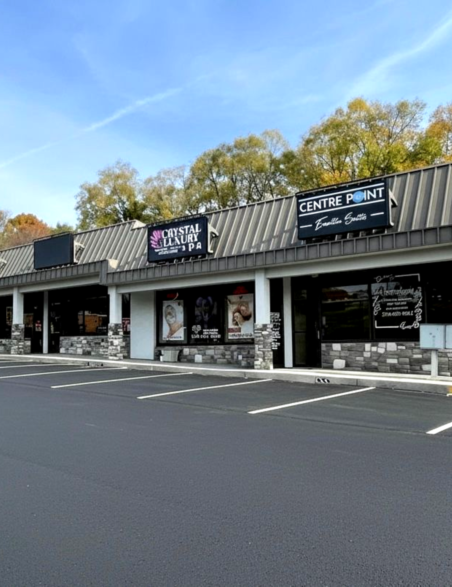 Strip mall with dental center and furniture store under a blue sky, with parking spaces visible.