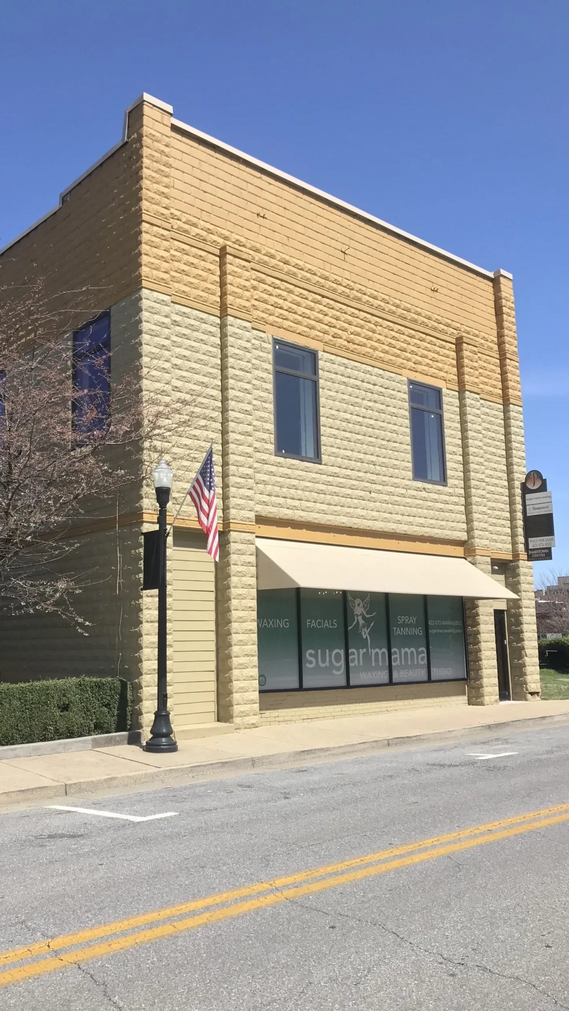 Two-story brick building with awning and American flag; 
