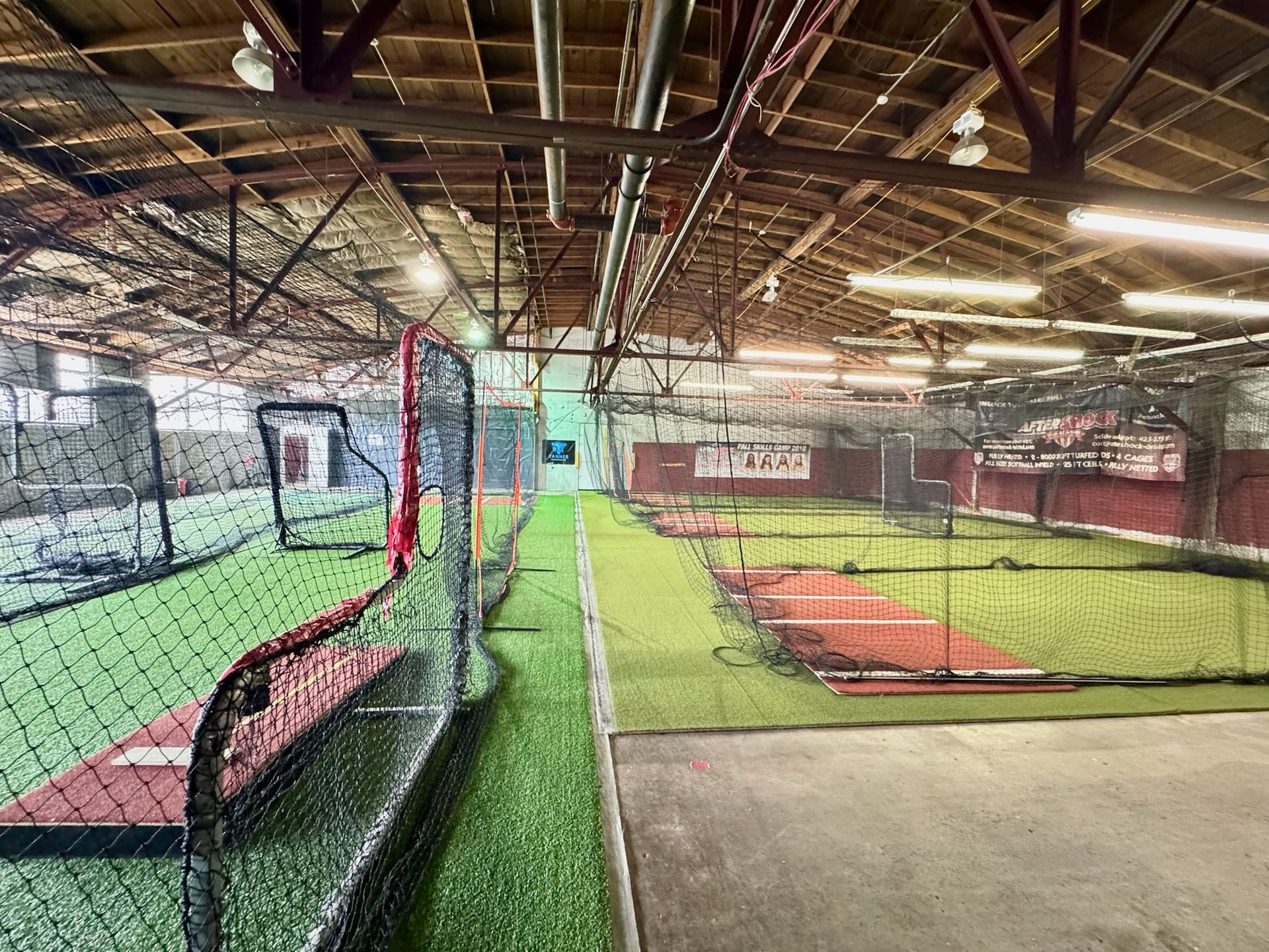 Indoor baseball training facility with batting cages and artificial turf.