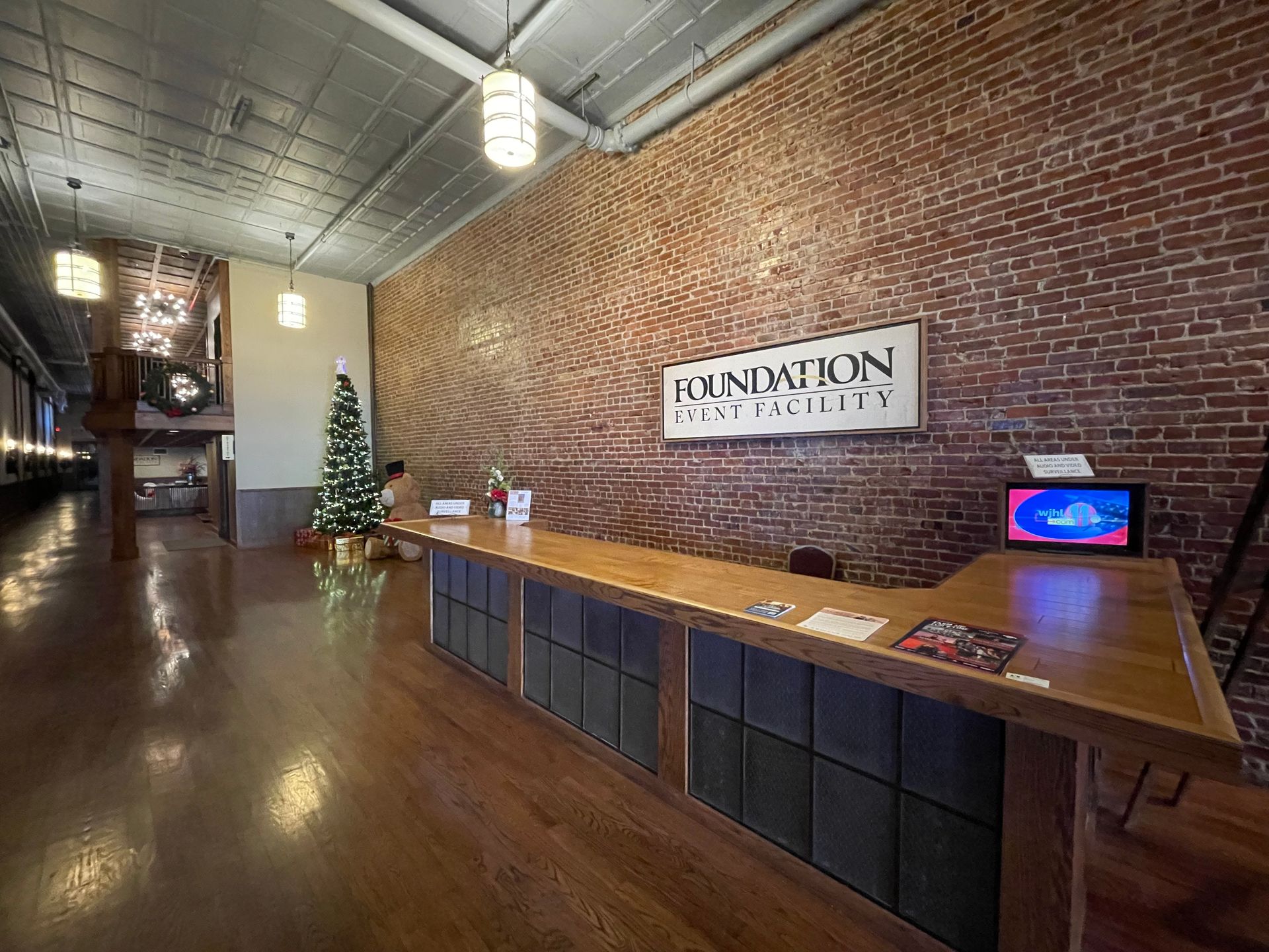 Lobby with a brick wall and a wooden reception desk. A sign reads 