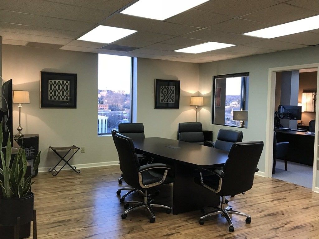 Meeting room with large dark table, leather chairs, and two framed wall art pieces.