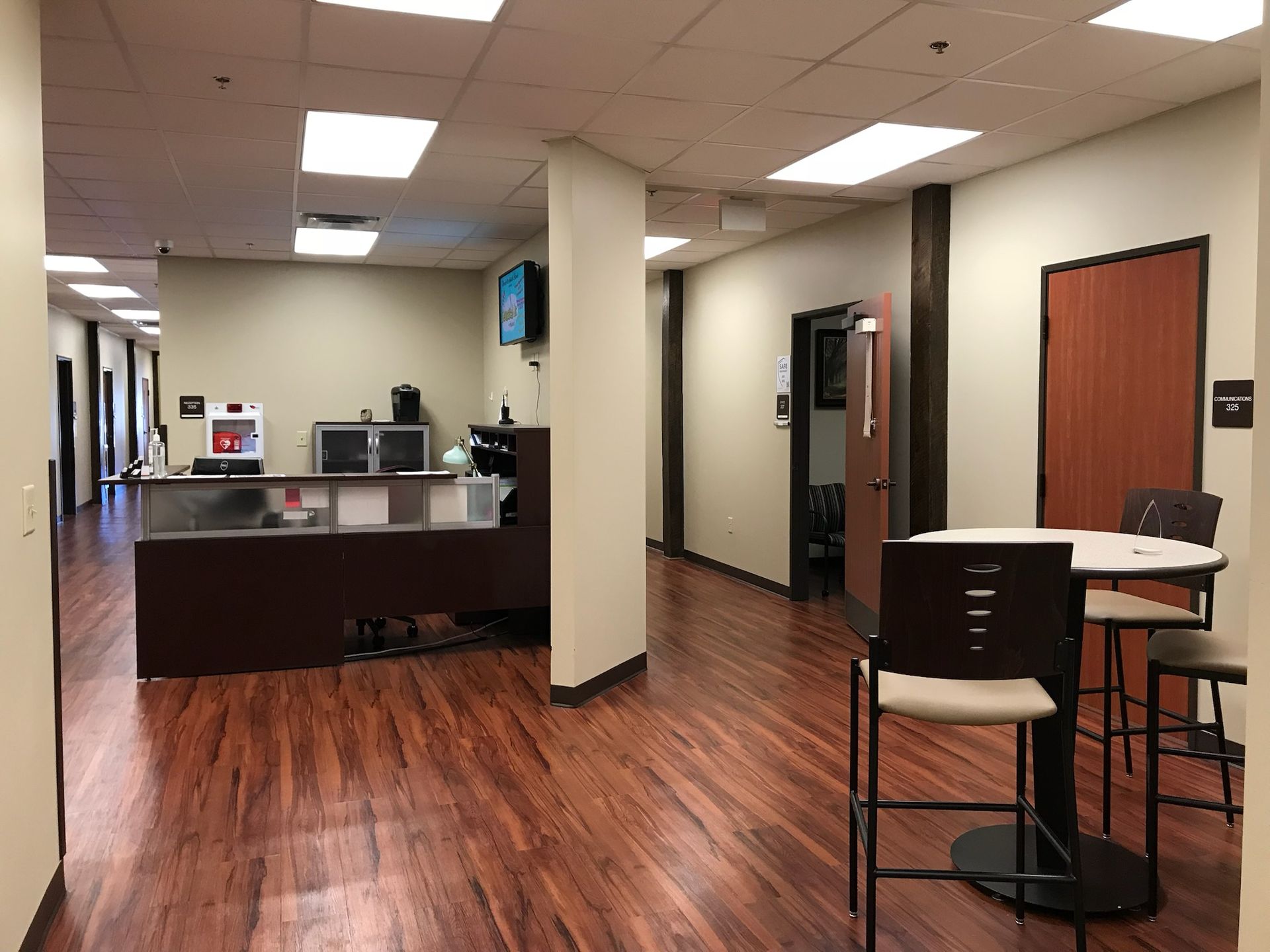 Interior office hallway with a reception desk, wood floors, and waiting area.