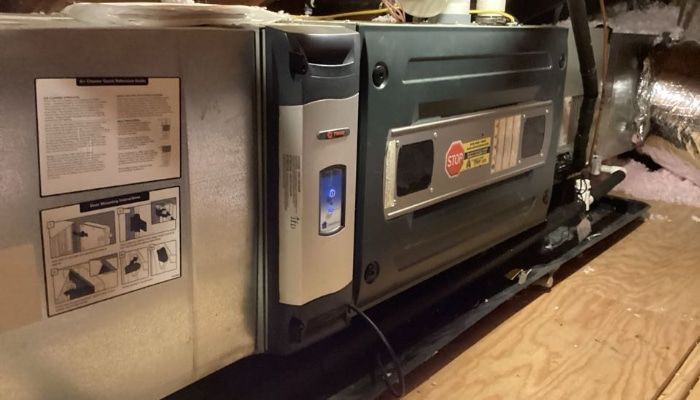 Furnace unit in a home's attic, with a control panel and ductwork.