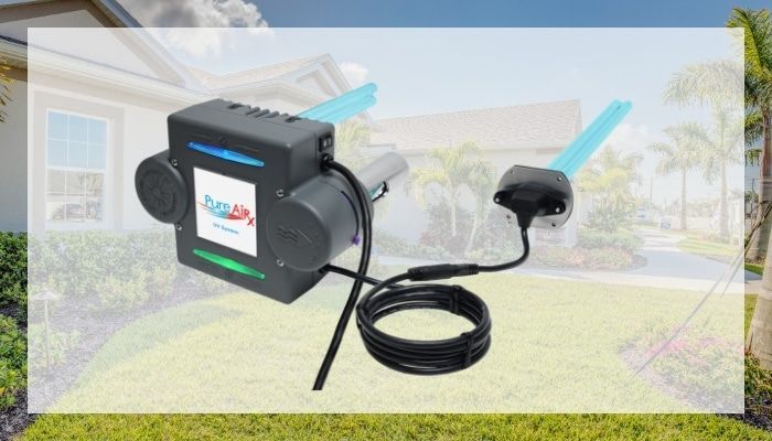 Black device with two blue tubes on grass in front of a house.