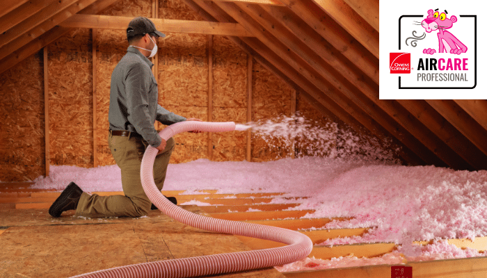 Man blowing pink insulation into an attic.