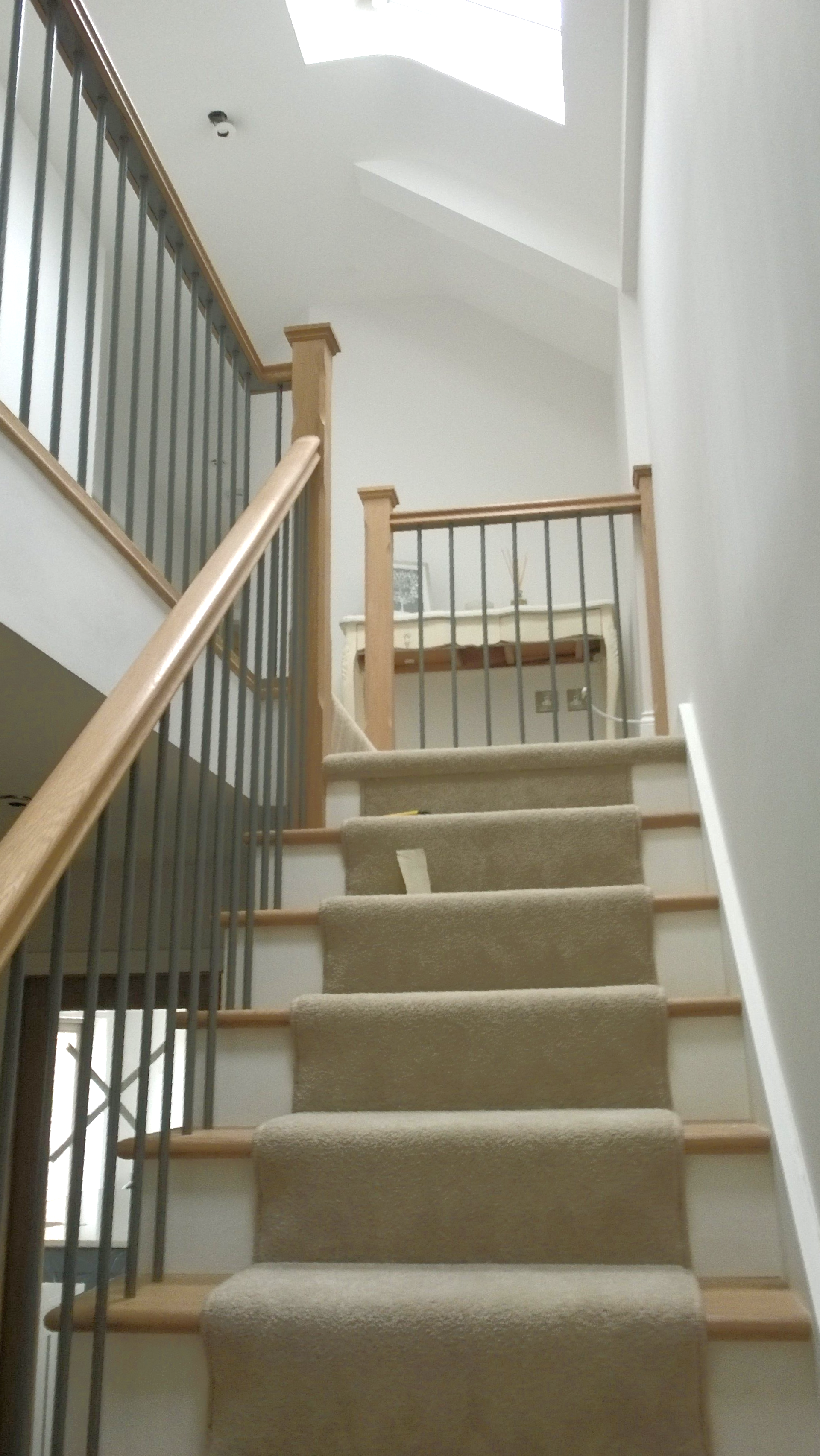 Staircase with tan carpet and wooden railings leads upwards, visible from the bottom.