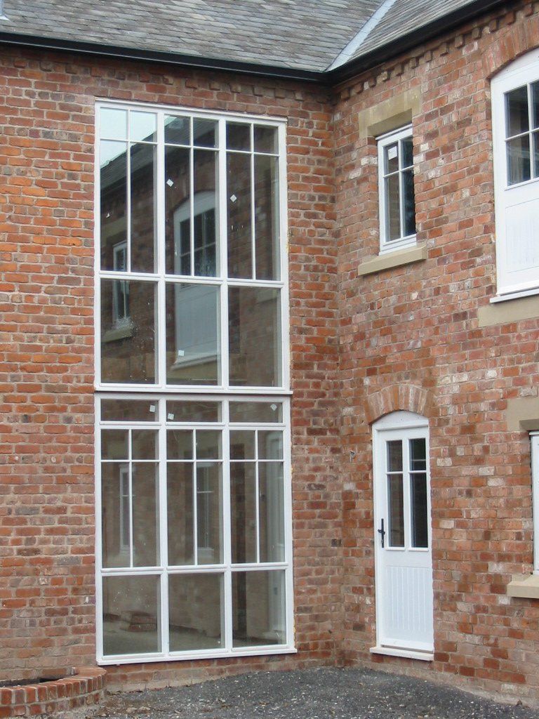 Two-story brick building with a large glass window and white door.