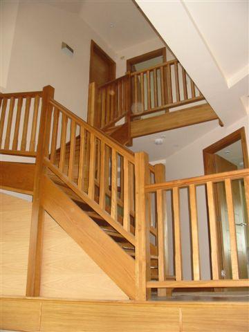 Wooden staircase with railings, leading to upper levels of a building.