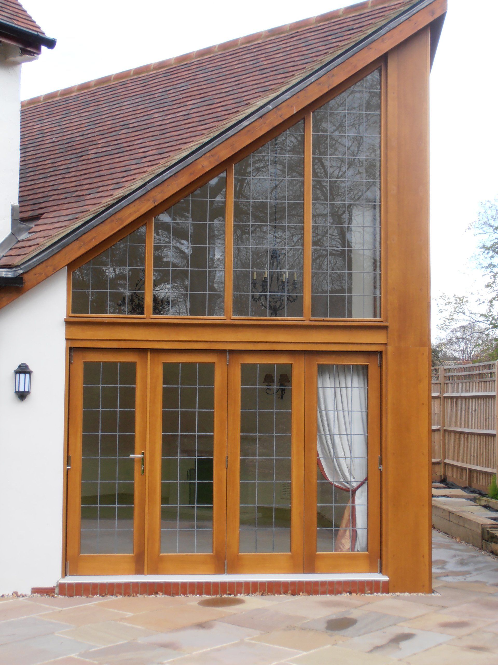 Glass doors and windows on a wooden frame, beneath a sloping roof.