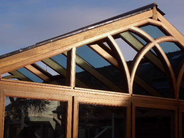 Wooden framed building with arched glass panels under a slanted roof.