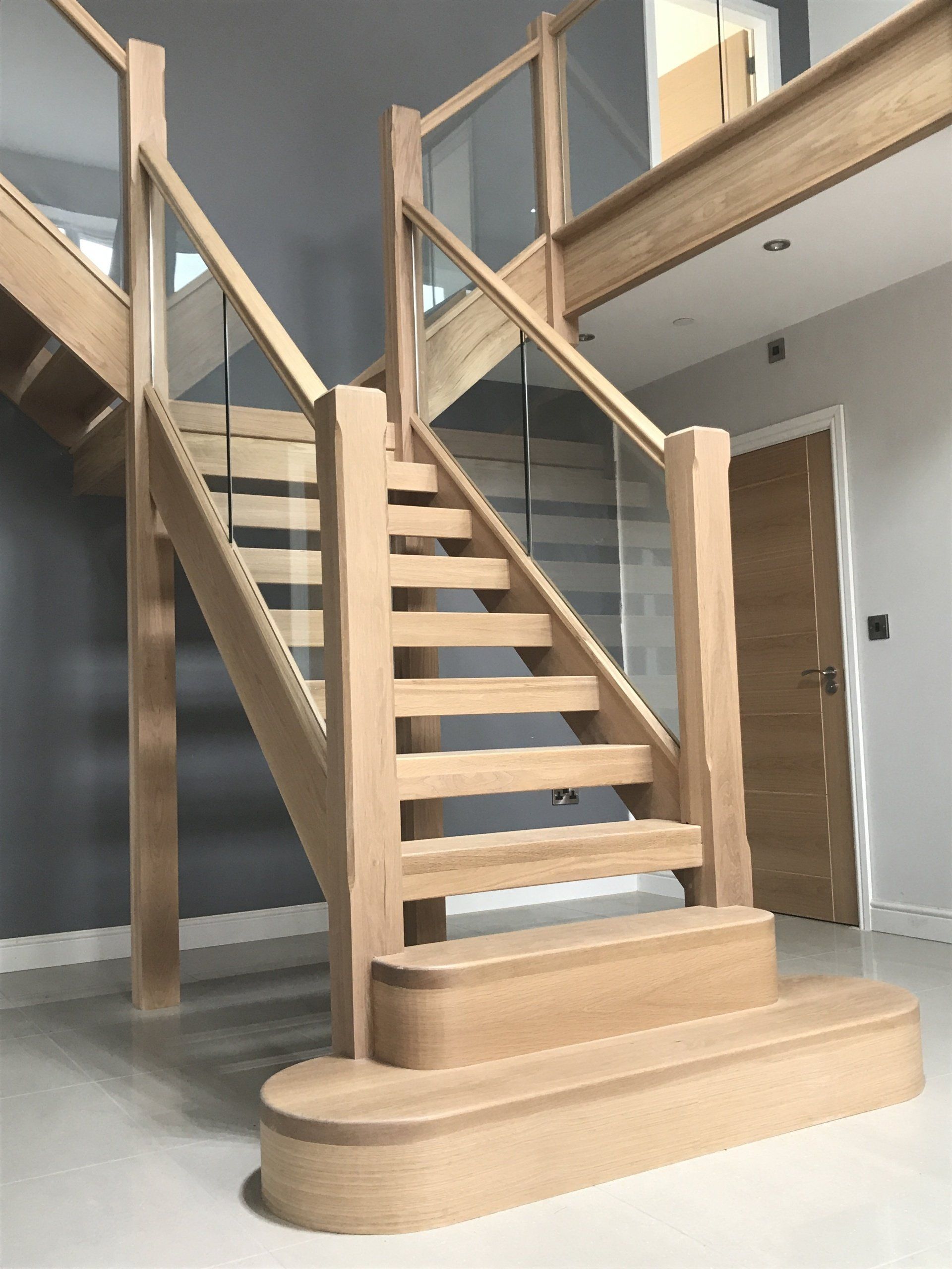 Wooden staircase with glass railing in a modern home.
